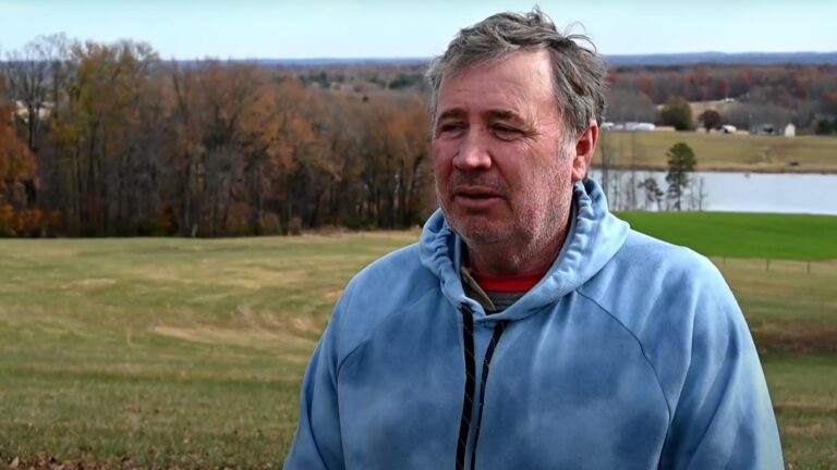 A man speaks in front of water