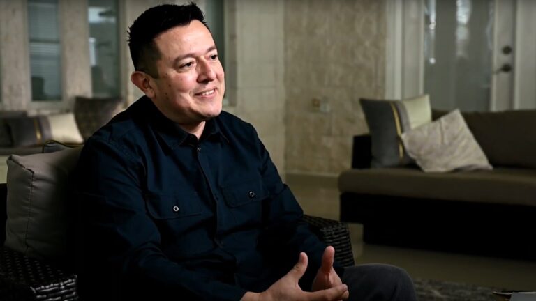A man in black shirt gestures while speaking