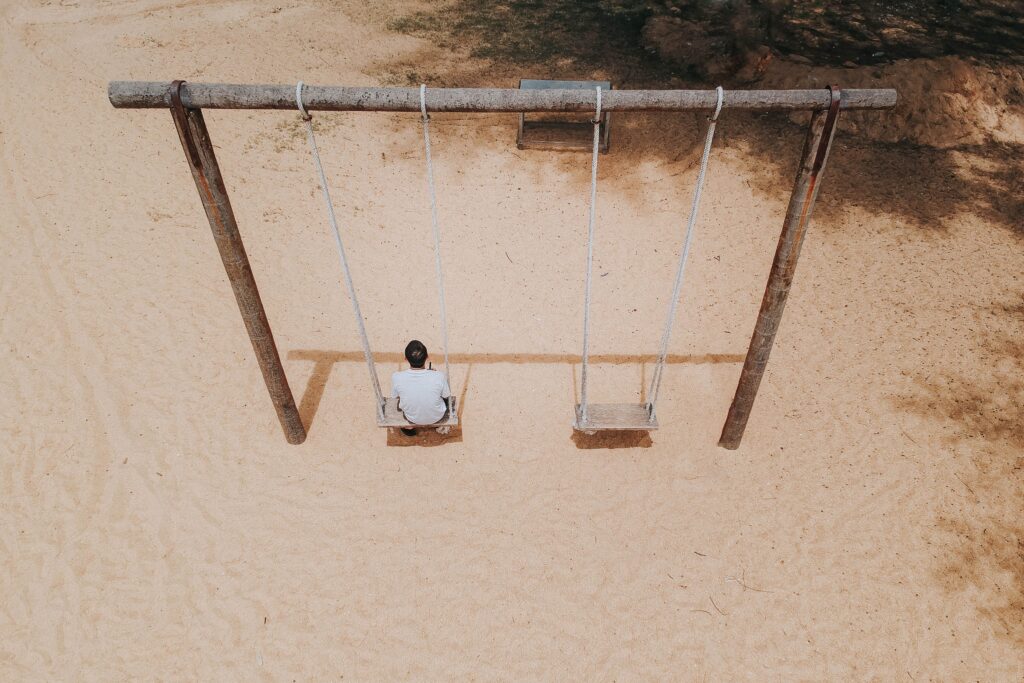 Person seating alone on a swing feeling loneliness
