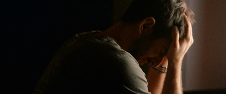 An overwhelmed man sits with his head in his hands