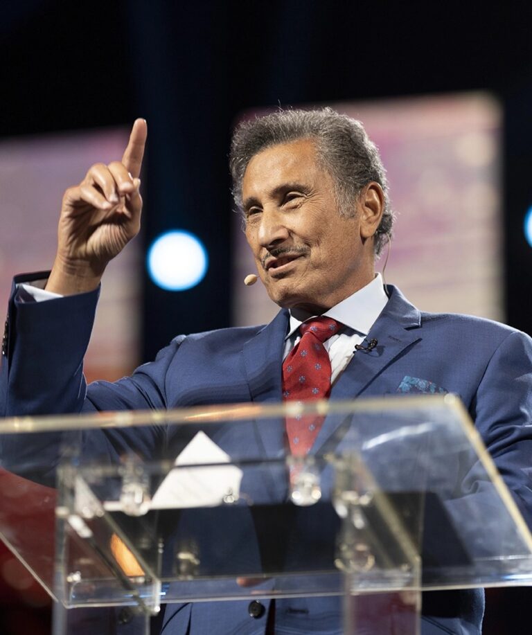 Dr. Michael Youssef standing in front of a podium pointing upwards